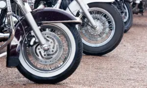A closeup shot of the front wheel of several motorcycles.