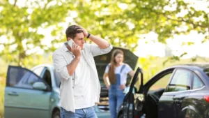 A car accident between two people and a man is on the phone.