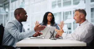 Two men arguing while a woman in the middle is trying to calm down the situation.