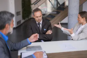 A frustrated man arguing with a woman while a man is trying to calm down the discussion.