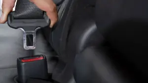 A person buckling up their seatbelt. 