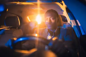 A man driving a car at night with great focus. 