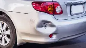 A gray car with an indent on its left bumper corner.