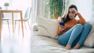 A woman on the couch looking at her phone for answers.